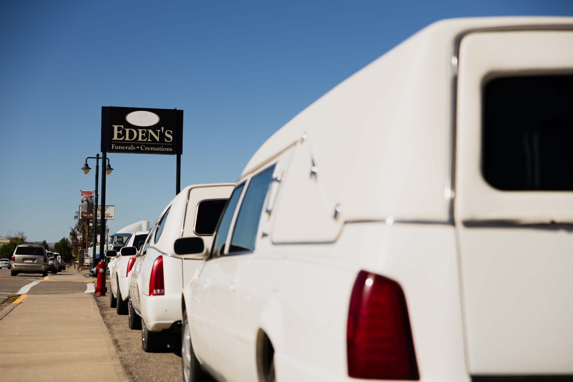 The Eden's Funerals & Cremations roadside sign above a white funeral coach, Fort Macleod.