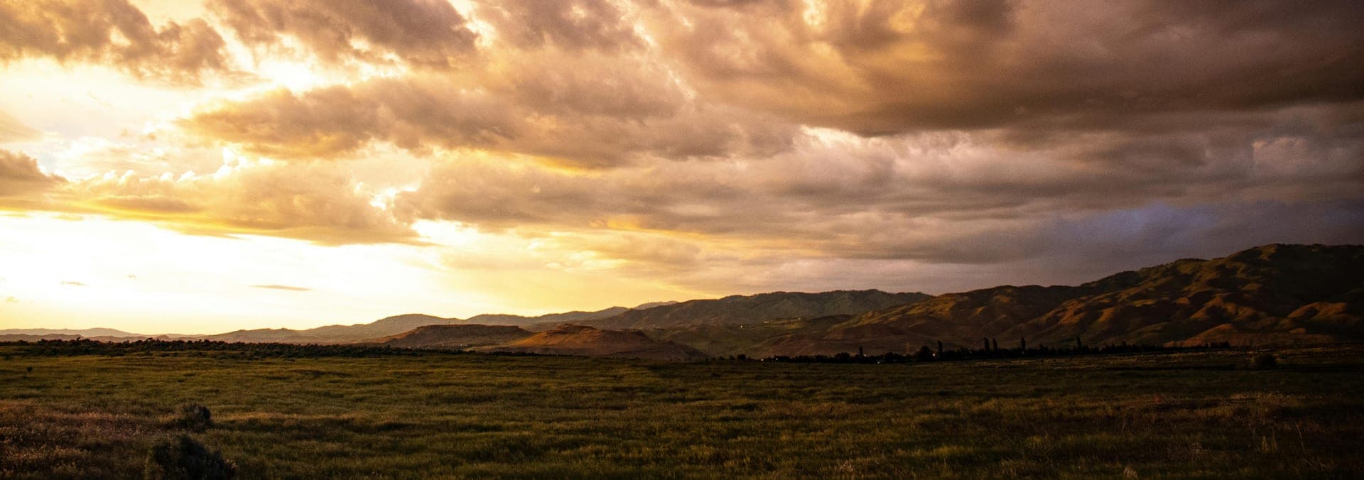 Storm clouds breaking over rolling prairie hills